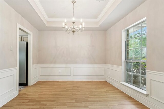 418 Westwood Dr, Mandeville, LA 70471 - empty room featuring a chandelier, light wood-type flooring, a tray ceiling, ornamental molding, and wainscoting