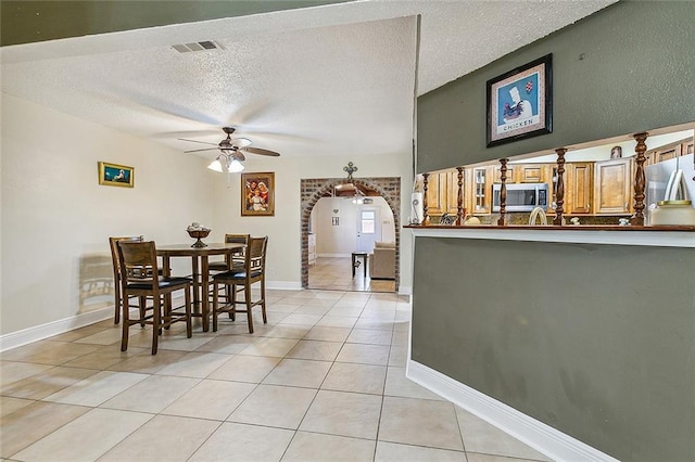1929 Jean Lafitte Blvd, Lafitte, LA 70067 - dining room featuring a ceiling fan, light tile patterned flooring, arched walkways, and a textured ceiling