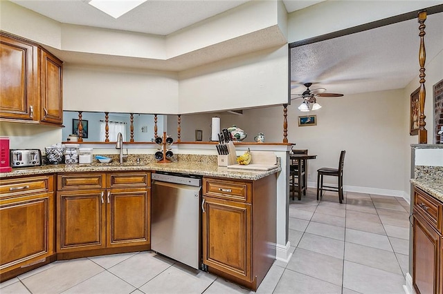 1929 Jean Lafitte Blvd, Lafitte, LA 70067 - kitchen featuring brown cabinetry, dishwasher, ceiling fan, light tile patterned floors, and light stone countertops