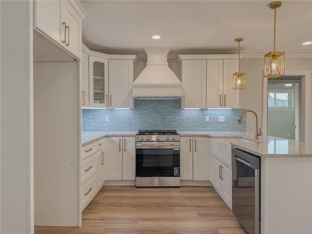 861 W William David Pkwy, Metairie, LA 70005 - kitchen featuring stainless steel appliances, premium range hood, a peninsula, white cabinetry, and tasteful backsplash