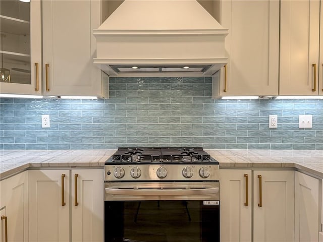 861 W William David Pkwy, Metairie, LA 70005 - kitchen featuring stainless steel range with gas cooktop, custom exhaust hood, light countertops, white cabinets, and glass insert cabinets