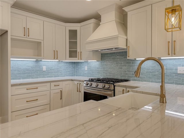 861 W William David Pkwy, Metairie, LA 70005 - kitchen featuring gas range, custom range hood, light stone counters, white cabinets, and tasteful backsplash