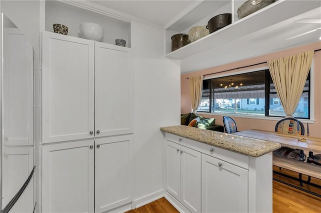 4430 Karen Ave, Jefferson, LA 70121 - kitchen with light wood-style floors, white cabinetry, light stone countertops, a peninsula, and crown molding