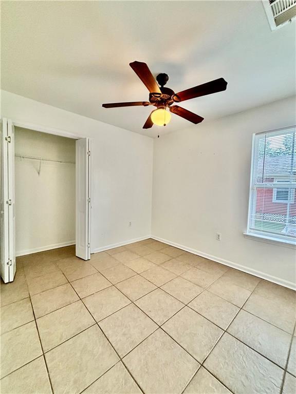 70330 C St, Covington, LA 70433 - unfurnished bedroom with light tile patterned floors, a closet, and a ceiling fan