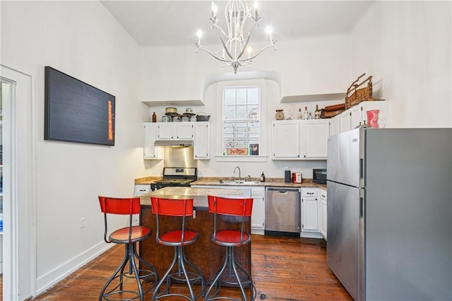 1821 Urquhart St, New Orleans, LA 70116 - kitchen featuring appliances with stainless steel finishes, a chandelier, dark wood-style floors, white cabinets, and a kitchen island