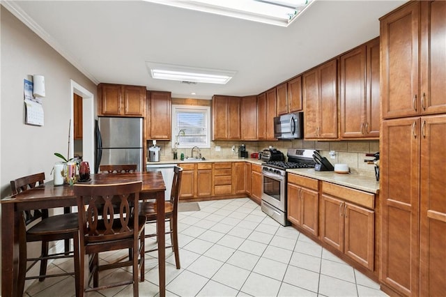 212 7th St, Bridge City, LA 70094 - kitchen with appliances with stainless steel finishes, backsplash, light countertops, brown cabinetry, and ornamental molding