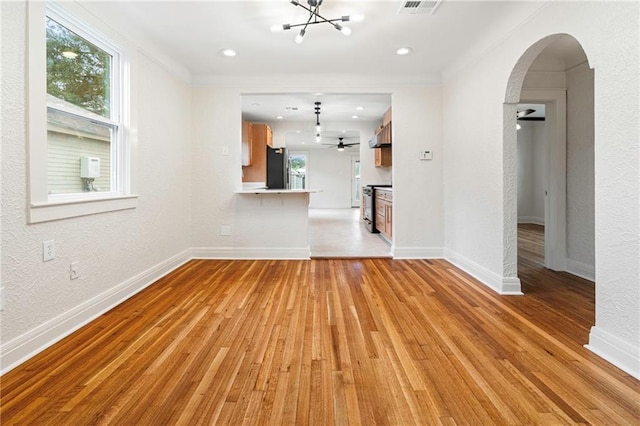 3821 Bauvais St, Metairie, LA 70001 - unfurnished living room with arched walkways, a chandelier, light wood-type flooring, a ceiling fan, and a textured wall