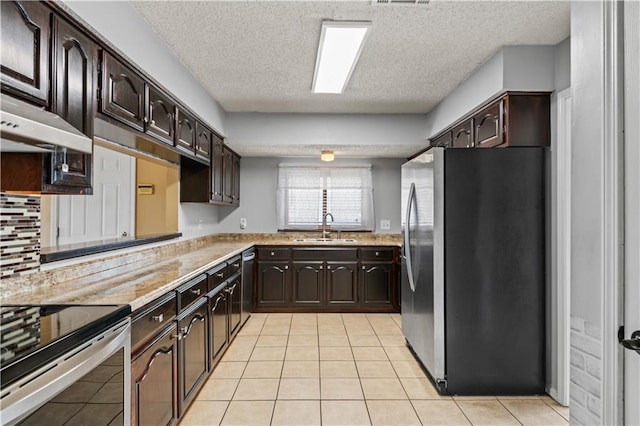 1701 Cambridge Dr, La Place, LA 70068 - kitchen featuring stainless steel appliances, light countertops, a textured ceiling, dark brown cabinetry, and light tile patterned floors