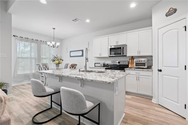16168 S Trace Ext, Ponchatoula, LA 70454 - kitchen with appliances with stainless steel finishes, a kitchen bar, a chandelier, white cabinetry, and light stone countertops