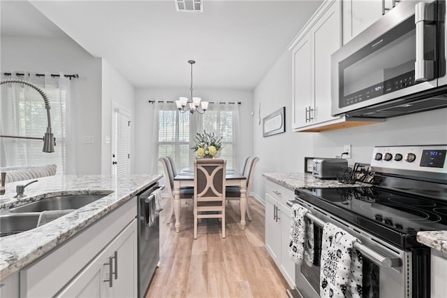 16168 S Trace Ext, Ponchatoula, LA 70454 - kitchen featuring appliances with stainless steel finishes, a chandelier, light wood finished floors, white cabinets, and hanging light fixtures