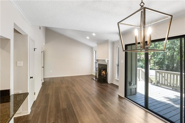 640 Tete Lours Dr Unit 1, Mandeville, LA 70471 - unfurnished living room featuring a chandelier, lofted ceiling, dark wood-style floors, a warm lit fireplace, and a textured ceiling