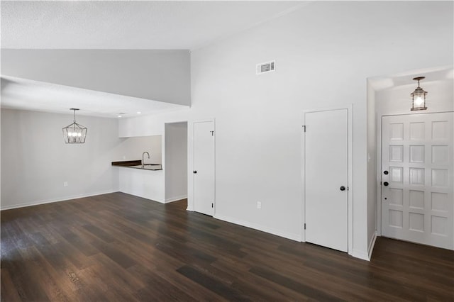 640 Tete Lours Dr Unit 1, Mandeville, LA 70471 - unfurnished living room with dark wood-type flooring, a chandelier, and high vaulted ceiling