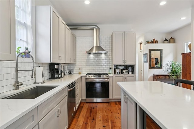 827 Port St, New Orleans, LA 70117 - kitchen featuring appliances with stainless steel finishes, wall chimney exhaust hood, backsplash, recessed lighting, and light wood finished floors