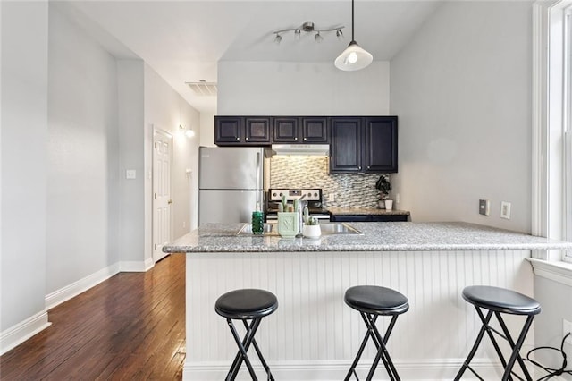 4528-30 Baudin St, New Orleans, LA 70119 - kitchen with freestanding refrigerator, dark wood-type flooring, a kitchen bar, tasteful backsplash, and decorative light fixtures