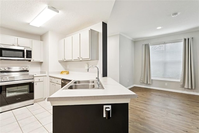 350 Emerald Forest Blvd Unit 6101, Covington, LA 70433 - kitchen featuring appliances with stainless steel finishes, a peninsula, light countertops, white cabinetry, and light wood-style floors