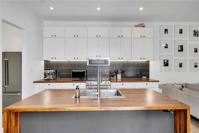 2113 Harmony St, New Orleans, LA 70115 - kitchen featuring wood counters, appliances with stainless steel finishes, decorative backsplash, a large island with sink, and recessed lighting