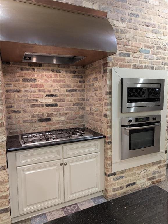 11 Mark Smith Dr, Mandeville, LA 70471 - kitchen featuring extractor fan, dark countertops, stainless steel appliances, white cabinets, and brick wall