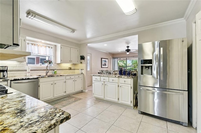 1109 Andrews Ave, Metairie, LA 70005 - kitchen featuring appliances with stainless steel finishes, light stone counters, decorative backsplash, light tile patterned floors, and a ceiling fan