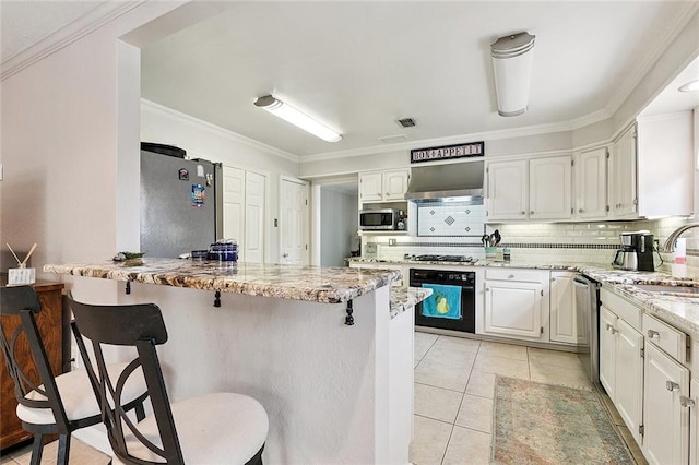 1109 Andrews Ave, Metairie, LA 70005 - kitchen featuring a kitchen breakfast bar, appliances with stainless steel finishes, decorative backsplash, white cabinets, and crown molding