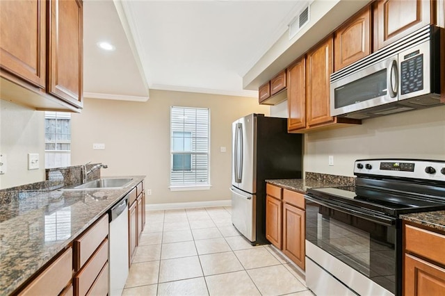 4339 Anthony St, Metairie, LA 70001 - kitchen featuring appliances with stainless steel finishes, ornamental molding, dark stone counters, brown cabinets, and light tile patterned floors