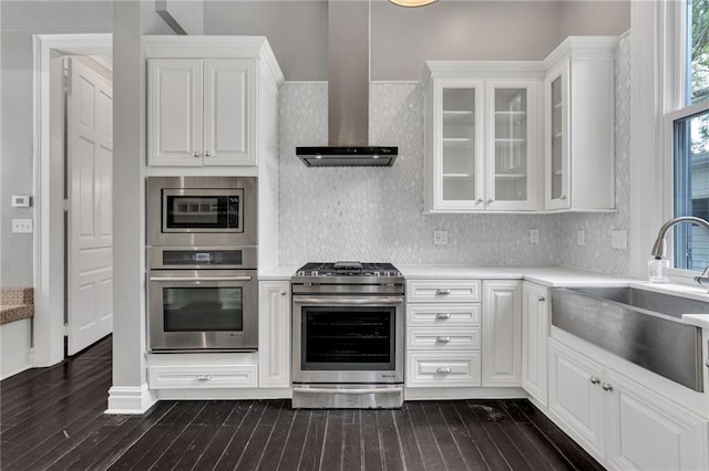 5349 Prytania St, New Orleans, LA 70115 - kitchen with stainless steel appliances, wall chimney range hood, light countertops, and dark wood-style flooring