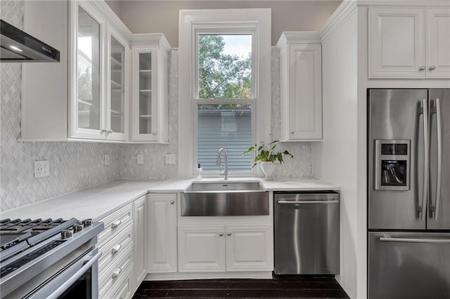 5349 Prytania St, New Orleans, LA 70115 - kitchen featuring stainless steel appliances, range hood, white cabinetry, glass insert cabinets, and tasteful backsplash