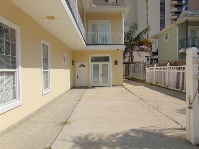 property entrance featuring a balcony, french doors, and a patio area