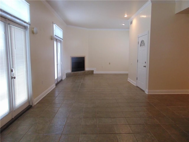 unfurnished living room with dark tile floors, a healthy amount of sunlight, and ornamental molding