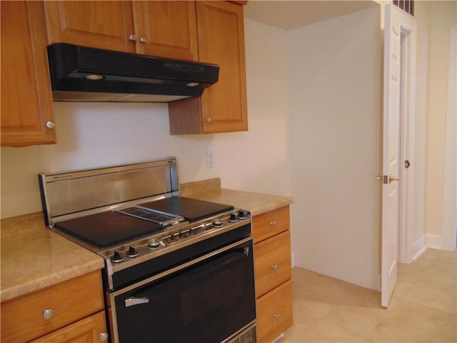 kitchen featuring light stone countertops, range, and light tile floors