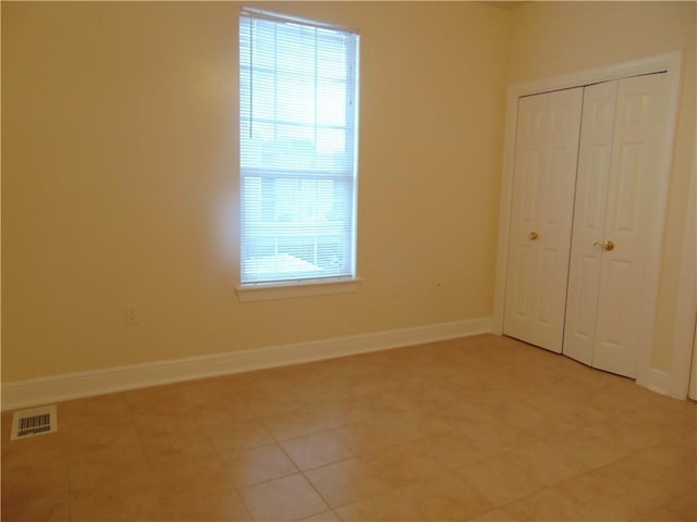 unfurnished bedroom featuring light tile floors, multiple windows, and a closet