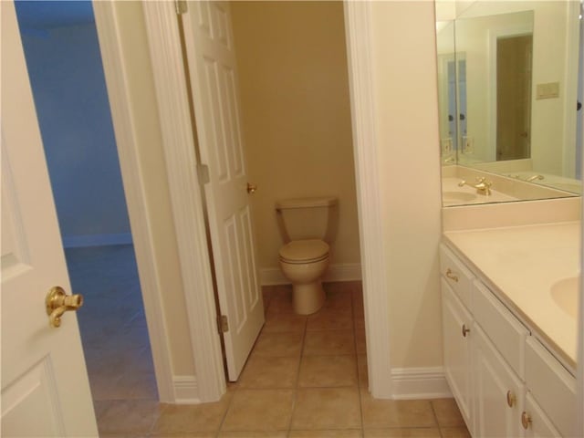 bathroom featuring toilet, vanity with extensive cabinet space, and tile flooring