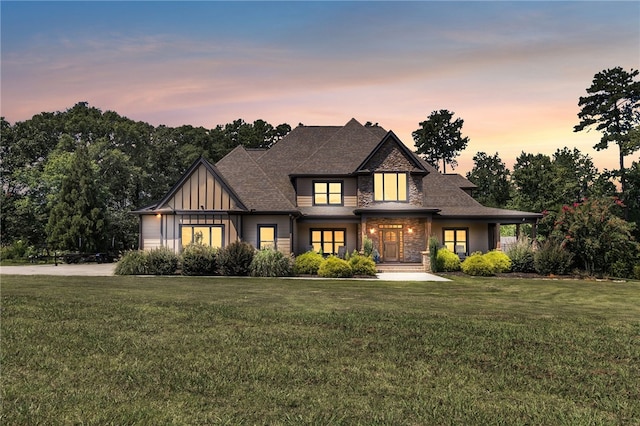 view of front of house featuring stone siding, a front lawn, board and batten siding, and roof with shingles