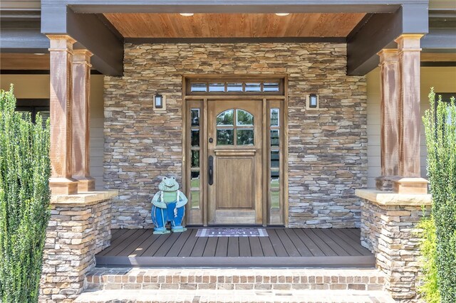 entrance to property with a porch and stone siding