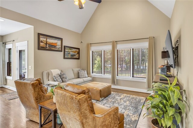 living room featuring high vaulted ceiling, a ceiling fan, baseboards, and wood finished floors