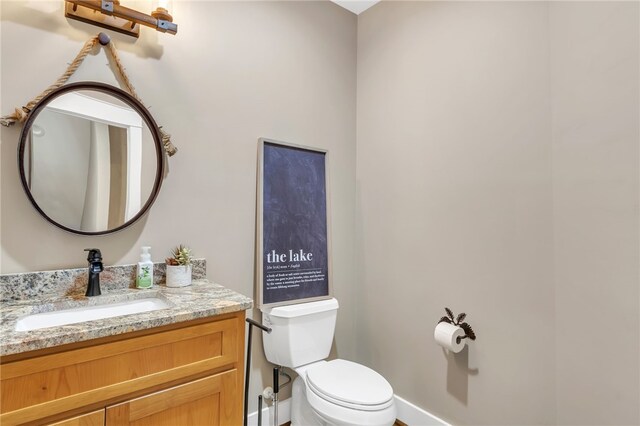 half bathroom featuring vanity, toilet, and baseboards