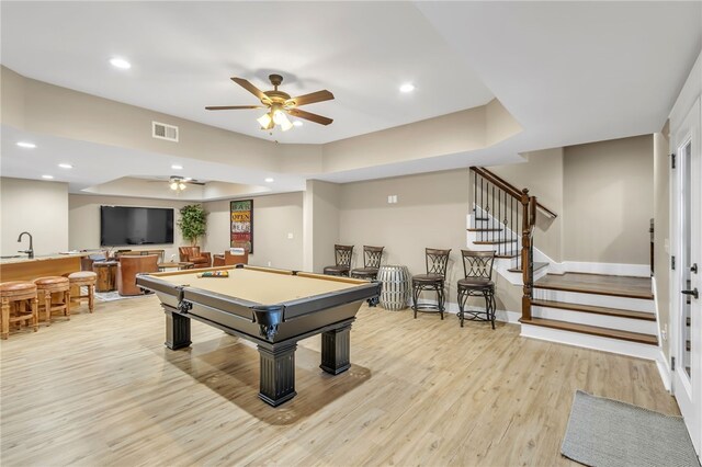 playroom with visible vents, a raised ceiling, light wood-type flooring, indoor wet bar, and recessed lighting