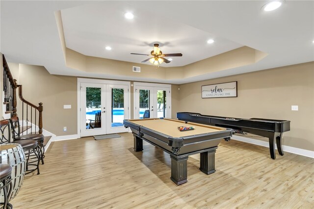 recreation room with a raised ceiling, visible vents, light wood finished floors, and french doors