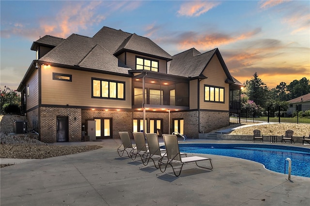 pool at dusk featuring a patio, cooling unit, fence, french doors, and a fenced in pool