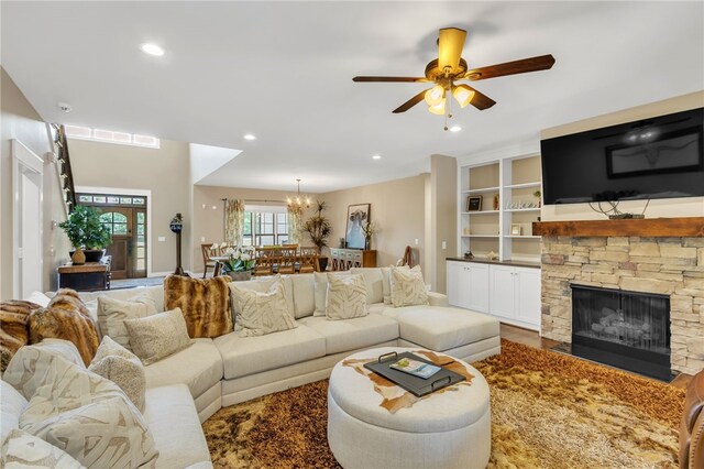 living area with recessed lighting, a stone fireplace, and ceiling fan with notable chandelier