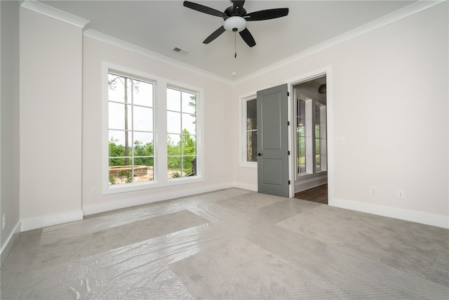 carpeted empty room with ceiling fan, ornamental molding, and a healthy amount of sunlight