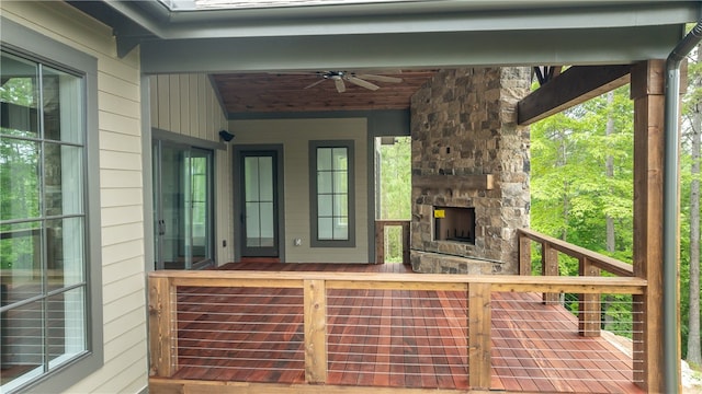 deck featuring an outdoor stone fireplace and ceiling fan