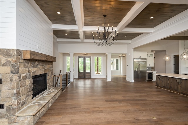 unfurnished living room with beamed ceiling, wood-type flooring, french doors, wooden ceiling, and a fireplace