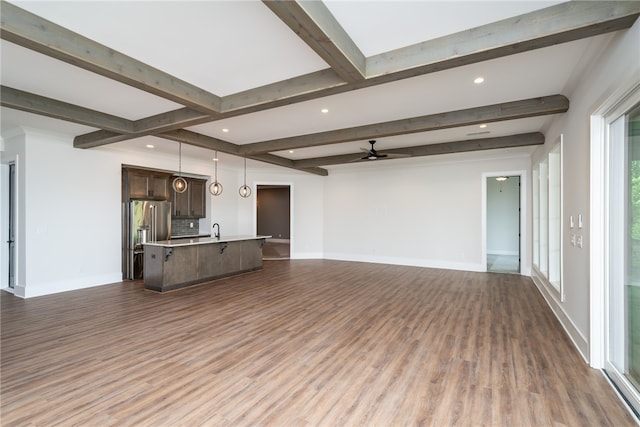 unfurnished living room featuring dark hardwood / wood-style floors, beamed ceiling, sink, and ceiling fan