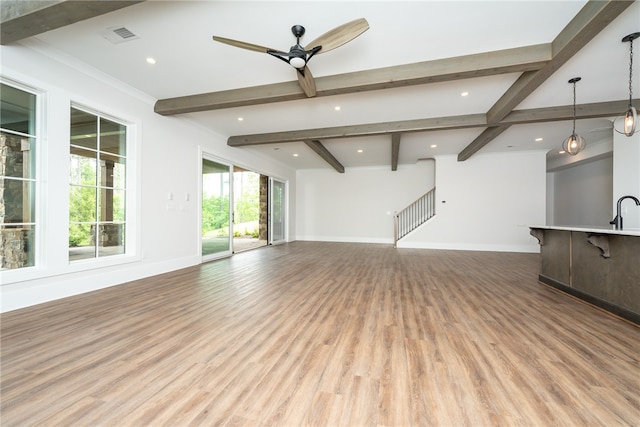 unfurnished living room featuring ceiling fan, beamed ceiling, and light wood-type flooring