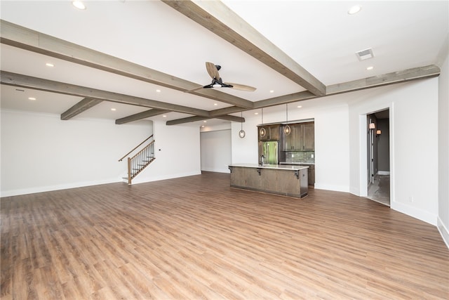 unfurnished living room featuring light hardwood / wood-style floors, beam ceiling, and ceiling fan