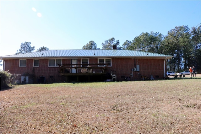 rear view of house featuring a lawn and a wooden deck