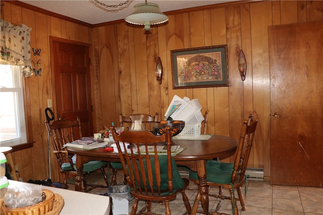 dining area featuring a textured ceiling, ornamental molding, wooden walls, and light tile patterned floors