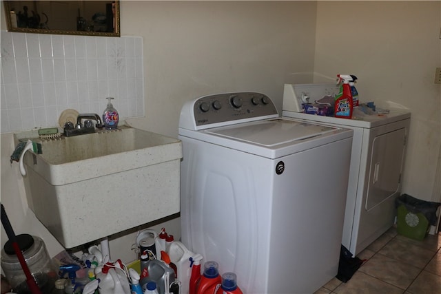 laundry area featuring light tile patterned floors, washer and clothes dryer, and sink