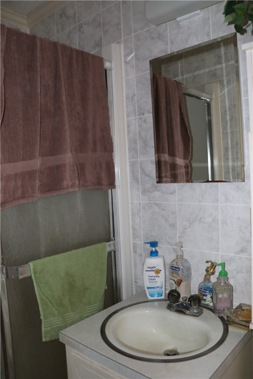 bathroom featuring tile walls, backsplash, vanity, and an enclosed shower