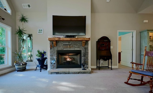 sitting room with a stone fireplace, carpet flooring, a high ceiling, and plenty of natural light